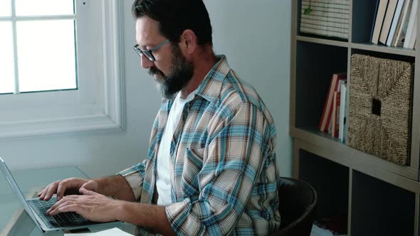Handsome young businessman in eyewear working with computer remotely, sitting at wooden table desk