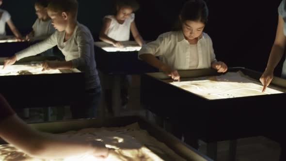 Art Teacher Talking to Children Making Sand Animation