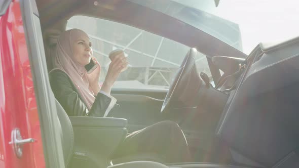 Pleasant Young Woman in Hijab Talking on Mobile and Drinking Coffee While