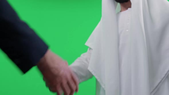 Arab Man in a White Kandura Makes a Good Deal with a Partner Buisnessman in a Suit a Handshake