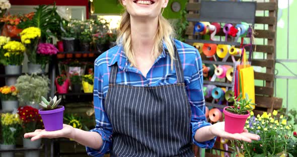 Female florist holding plant pot in flower shop