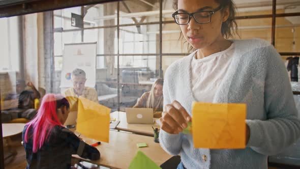 Young African American Lady Looking at Glass Wall and Glueing Sticker with Idea on It Slow Motion