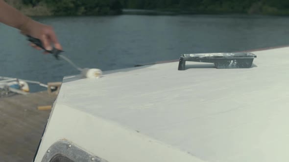 Painting roof planks using roller on wood boat. MEDIUM SHOT