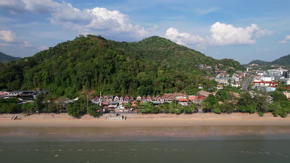 aerial drone flying parallel to Ao Nang Beach in Krabi Thailand revealing buildings and a large moun