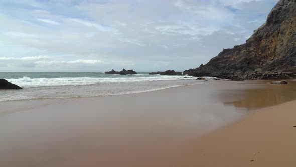 Atlantic Ocean Waves Crash on Beach near Gruta da Adraga Mountain