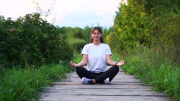 Young Nice Caucasian Woman in Sport Wear with White T-shirt Relaxing By Practicing Yoga Lotus