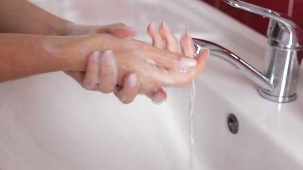 Woman Washes Her Hands in the Bathroom with Water Soap and Foam