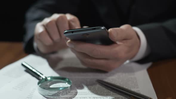 Business Expert Scrolling Financial News Feed on Smartphone, Working on Contract