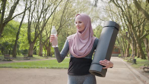 Charming Woman in Hijab and Sport Clothes Standing at Green Park and Holding