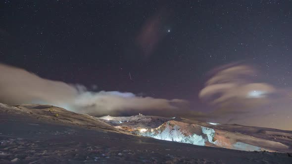 Timelapse of the night sky over ski area of snowy mountain landscape with radio telescope, Sierra Ne