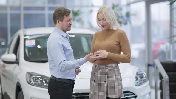 Wealthy Caucasian Man Giving Car Keys To Slim Beautiful Woman in Slow Motion