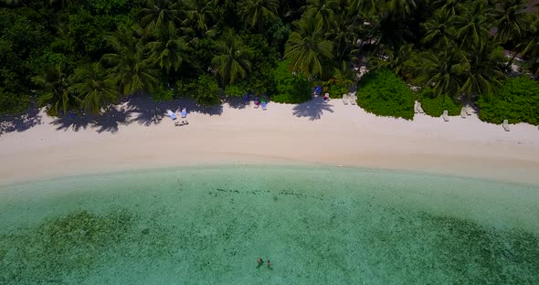Daytime birds eye travel shot of a white sand paradise beach and aqua turquoise water background in 