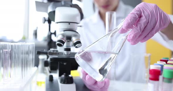 Scientist Holds Glass Flask with Clear Liquid in Laboratory