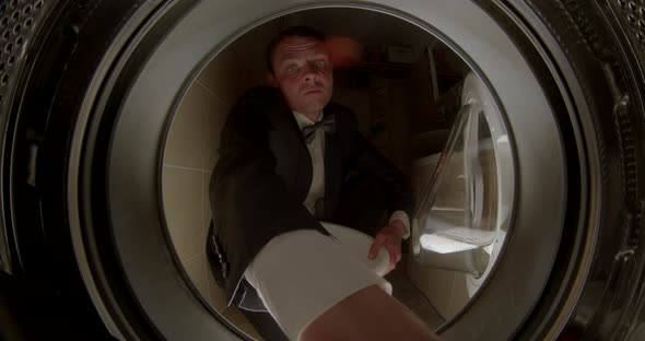 Man in a Suit Takes Clothes Out of the Washing Machine