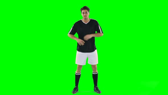 Confident football player standing against green screen