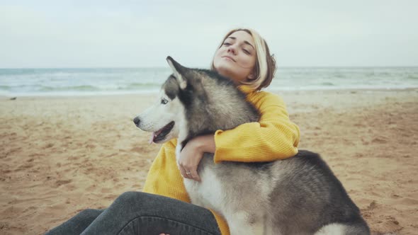 Young Beautiful Female Walking with Siberian Husky Dog on the Beach