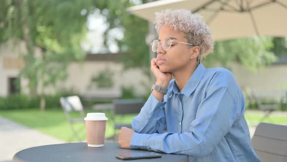 Young African Woman with Coffee Taking Nap in Outdoor Cafe