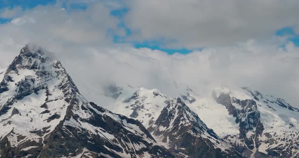 Air Flight Through Mountain Clouds Over Beautiful Snowcapped Peaks of Mountains and Glaciers