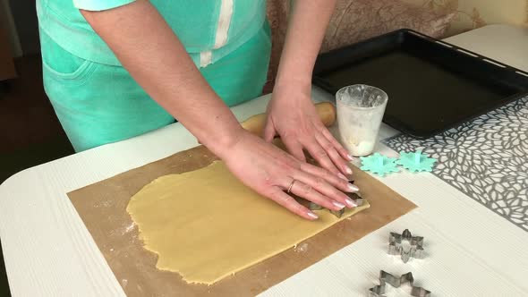 A Woman Squeezes Cookies Out Of Rolled Out Dough.