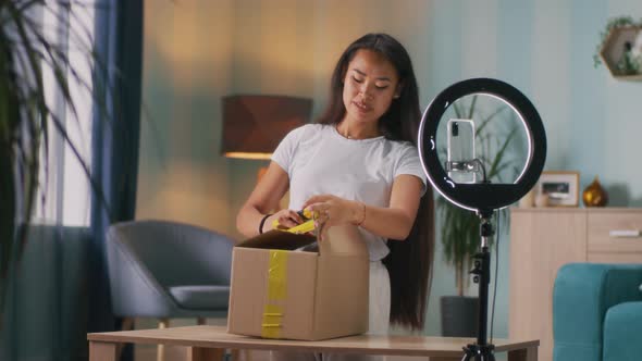 Asian Blogger Opening Parcel at Home