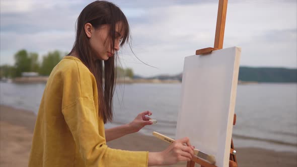 A Creative Woman Artist Prepares a Canvas with a Large Brush and a Solution