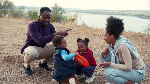 Happy African family playing in frisbee game near the river