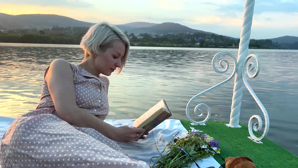 A Girl on a Raft Reads a Book in the Middle of the Lake