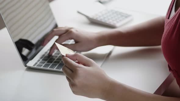 Asian woman using a laptop shopping online and use a credit card payment.