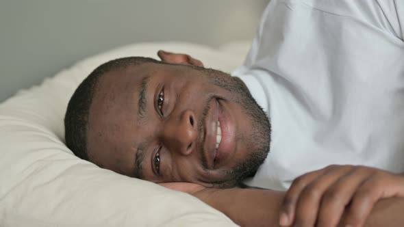 Young African Man Smiling at Camera in Bed