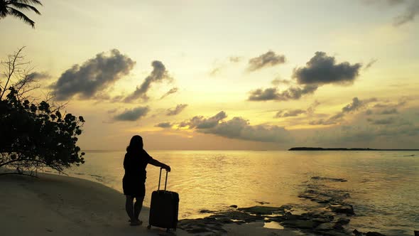 Young happy lady on photoshoot spending quality time at the beach on sunny blue and white sand backg