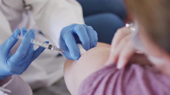 Caucasian woman and female doctor wearing face masks, vaccinating