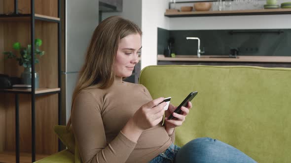 Happy Young Woman Shopping Online While Resting on Sofa at Home. Smiling Woman Online Banking Using