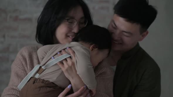 mother holds son in arms and adores him and hugs him tightly and plays with him