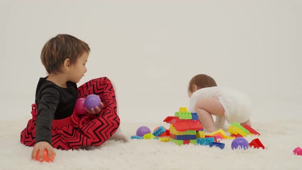 Toddler Girl Wearing Diaper and Her Sister Playing with Balls