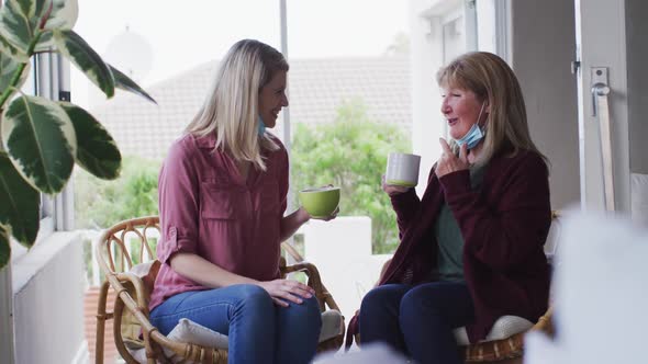 Mother and daughter talking to each other while drinking coffee at home