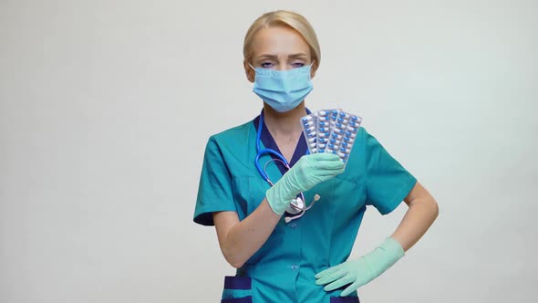 Medical Doctor Nurse Woman Wearing Protective Mask and Rubber or Latex Gloves - Holding Pills