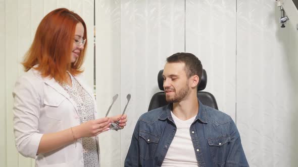 Consultant in the Optics Salon Helps a Young Man To Choose the Right Glasses for Vision