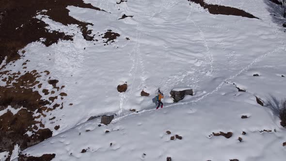 Hiker walking through snow in mountains, waving at camera