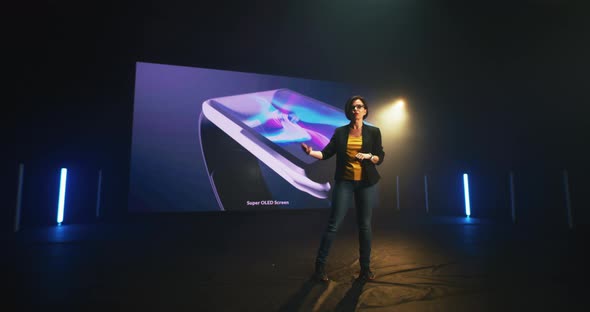 Woman Demonstrating Smartphone and Smart Watch on Stage