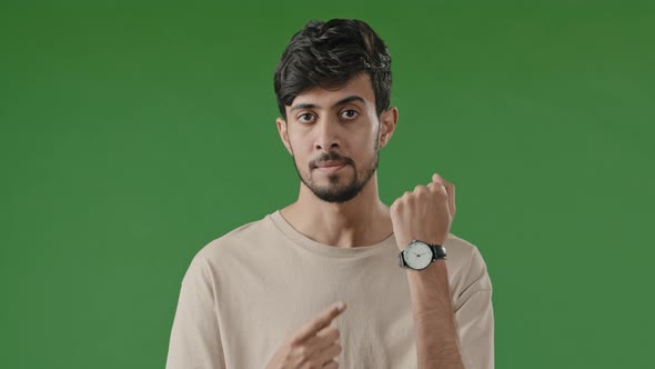 Portrait of Male Frustrated Indian Hispanic Guy Young Man Standing Over Green Background Waiting for