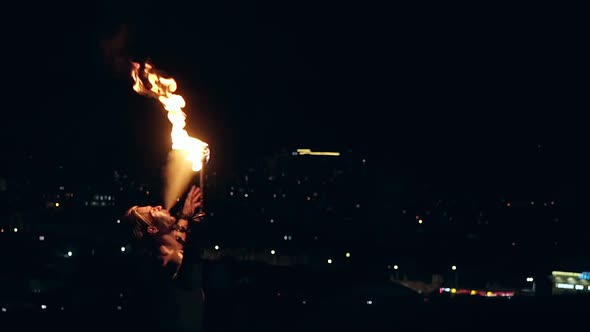 Young Blond Male Breathes Out Large Stream of Fire Making Fireball on Black Background