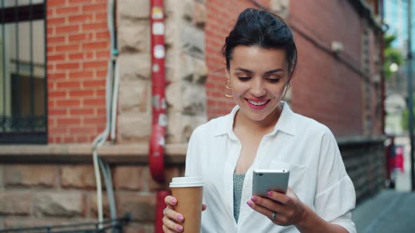 Slow Motion of Beautiful Lady Using Smartphone Holding Coffee Walking Smiling