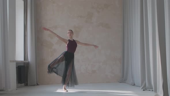 Flexible Ballerina in a Black Transparent Skirt Performs a Pirouette Movement By the Window