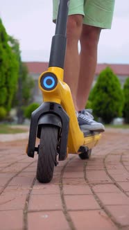 men's feet in sneakers, riding through streets of city on electric scooter