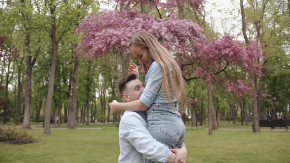 A Young Man Holds His Beloved in His Arms and Whirls with Her Near a Blossoming Tree