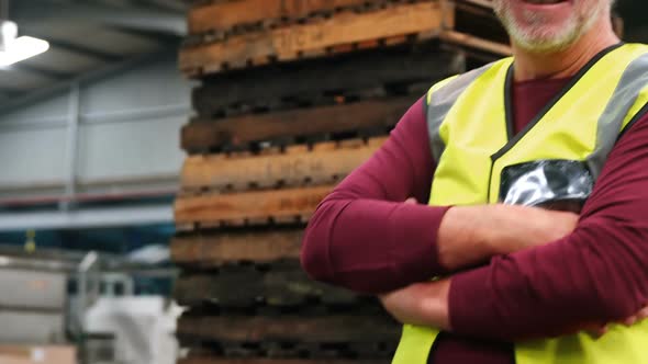 Worker standing with arms crossed in factory