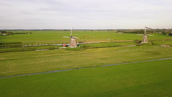 Two Static Windmills On Lush Wind Farm In The Hague Netherlands On A Sunny Day Drone Shot (Approach