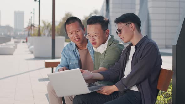 Three Asians Working on Laptop Outdoors