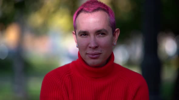 Young Man with Pink Hair and Piercing in Ears and Nose Is Smiling Outdoors, Portrait