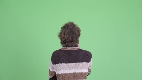 Rear View of Young Man with Curly Hair Thinking and Pointing Finger